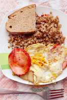 dish from boiled buckwheat fried piece of sausage and fried eggs