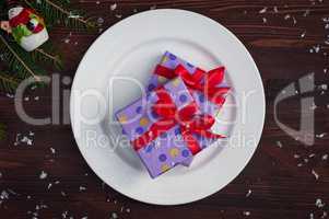 Two gift wrapped in paper with a red ribbon on a white plate