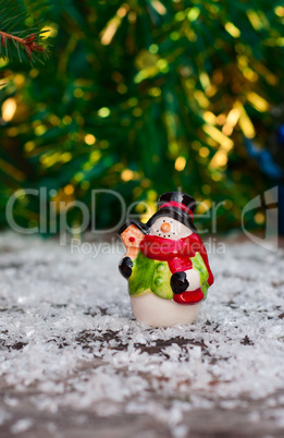 Ceramic snowman among the snow on blurred background Christmas l