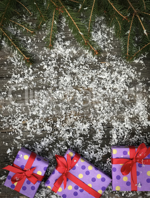 Christmas gray wooden background with snow, gifts and fir branch