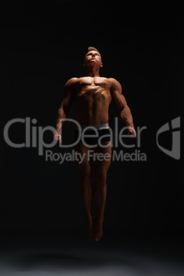 Muscular bodybuilder posing on black background.