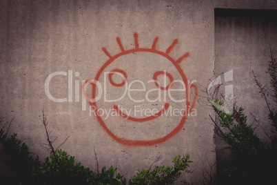Graffiti painting of red happy smiley face on a concrete wall