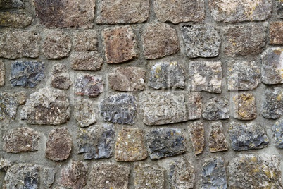 Texture of gray stone wall covered with lichen