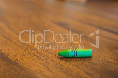 Green color pastel crayon on brown wooden table
