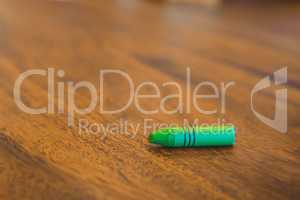 Green color pastel crayon on brown wooden table