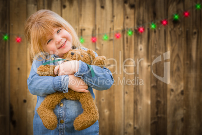 Girl Holding Teddy Bear In Front of Wooded Background with Chris