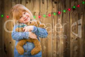 Girl Holding Teddy Bear In Front of Wooded Background with Chris