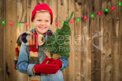 Happy Boy Wearing Santa Hat Holding Christmas Tree On A Wood Fen