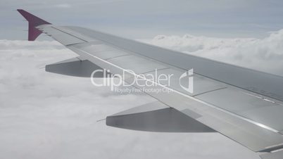 Wing of airplane flying above the clouds in sky