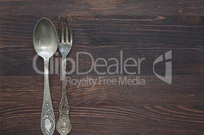 Old spoon and fork on brown wooden surface