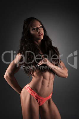 Bodybuilder girl posing topless in studio.