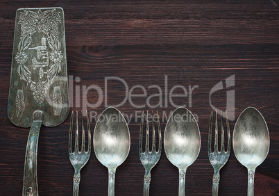 Vintage cutlery on brown wooden surface, top view, an empty spac