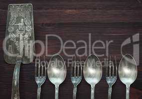 Vintage cutlery on brown wooden surface, top view, an empty spac