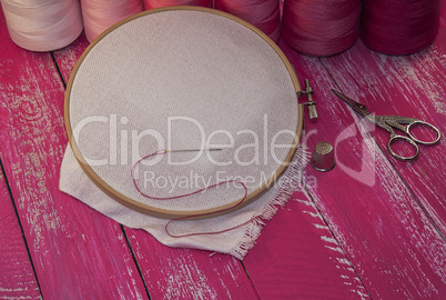 thread and  fabric in the wooden embroidery frame for needlework