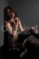 Sexy brunette sitting in corner with chains