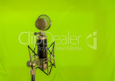 Vocal condenser microphone with wind screen isolated on green ba