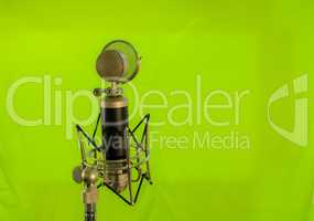 Vocal condenser microphone with wind screen isolated on green ba