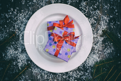 Plate with a gift on a gray wooden surface