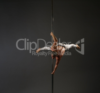 Pole dancer making exercises studio shot