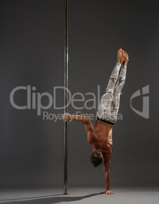 Pole dancer making exercises on pylon studio shot