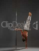 Pole dancer making exercises on pylon studio shot