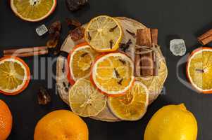 Fresh and dried oranges and lemons on a black surface