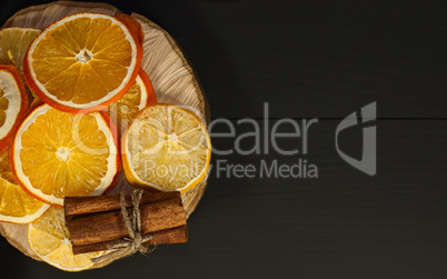 Dried citrus fruits on a black wooden surface, top view,
