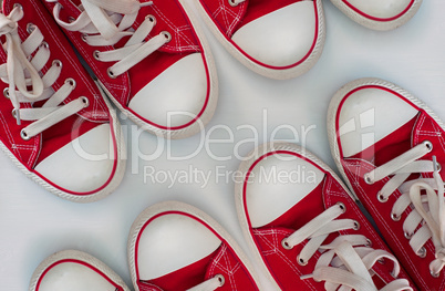 Four pairs of red sneakers on a white wooden surface
