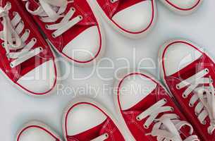 Four pairs of red sneakers on a white wooden surface