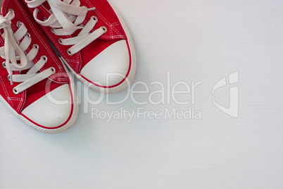 pair of red sneakers youth on a white wooden surface