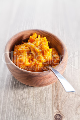 Pumpkin puree with a spoon on a wooden surface
