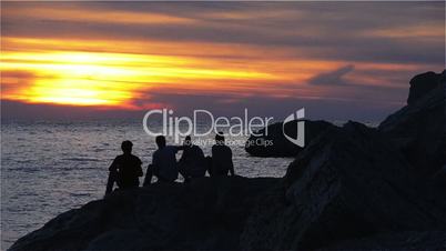 Teenagers Sitting on a Rock and Having Fun at Sunset