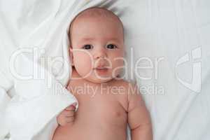 Baby boy lying on white linen close up studio shot