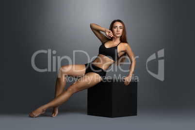Sexy slim woman posing in black lingerie on cube