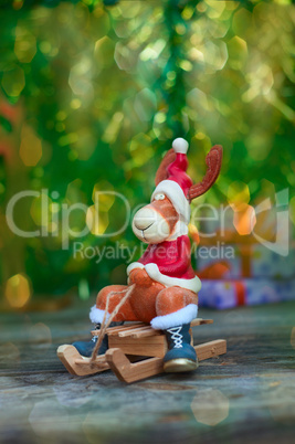 Christmas moose in holiday clothes on wooden sled