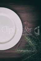 Half of an empty white plate on brown wooden surface