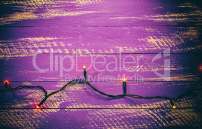 Lilac shabby wooden background with electric garland