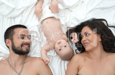 Loving parents with newborn baby in bed together