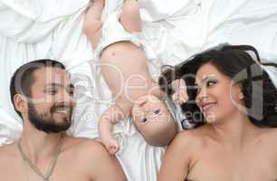 Loving parents with newborn baby in bed together