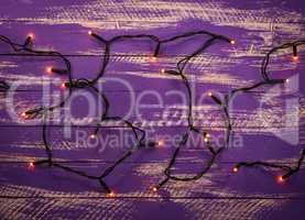 Purple wooden background with electric Christmas garland