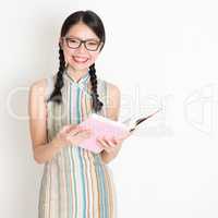 Oriental girl reading book and smiling