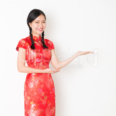 Oriental girl in red qipao hand showing something