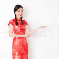 Oriental girl in red qipao hand showing something