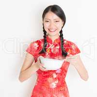 Oriental female in red cheongsam eating with chopsticks