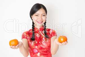 Oriental woman in red qipao holding mandarin orange