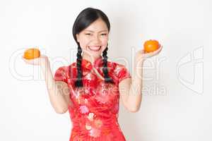 Oriental girl in red qipao holding mandarin orange