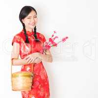 Oriental woman in red cheongsam holding gift basket