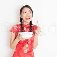 Oriental woman in red qipao eating with chopsticks