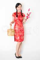 Oriental girl in red qipao holding gift basket