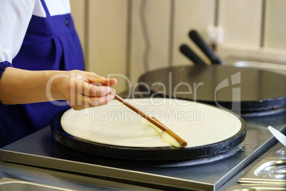 Close-up of cook frying crepe or pancake